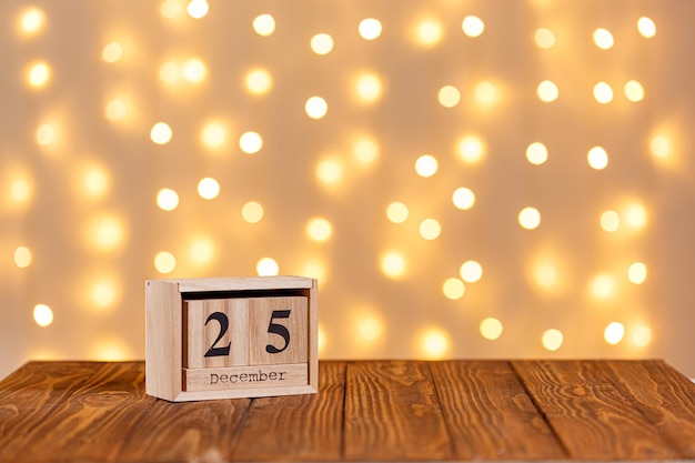 Kerst houten kalender 25 december op houten achtergrond en verlichting achtergrond