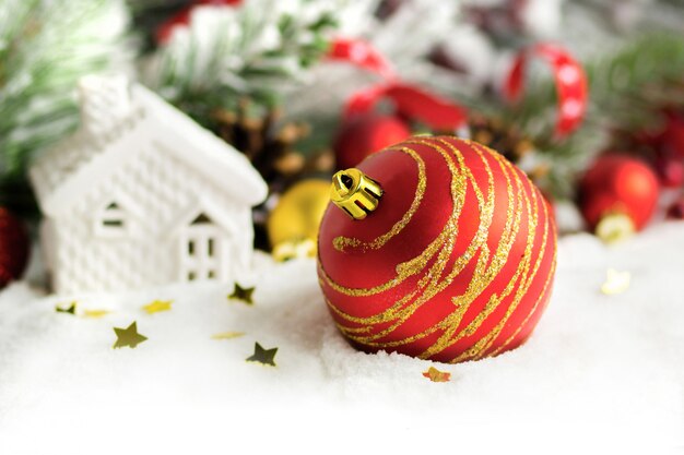 Kerst huis, kerstballen en takken close-up op sneeuw