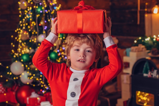 Kerst jongen. gelukkig weinig glimlachende jongen met de doos van de kerstmisgift. kerstviering vakantie. schattig