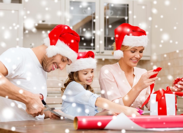 kerst, kerst, winter, familie, geluk en mensen concept - lachende familie in santa helper hoeden met geschenkdoos