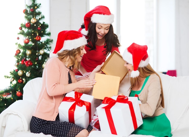 kerst, kerst, winter, geluk concept - drie lachende vrouwen in santa helper hoeden met veel geschenkdozen