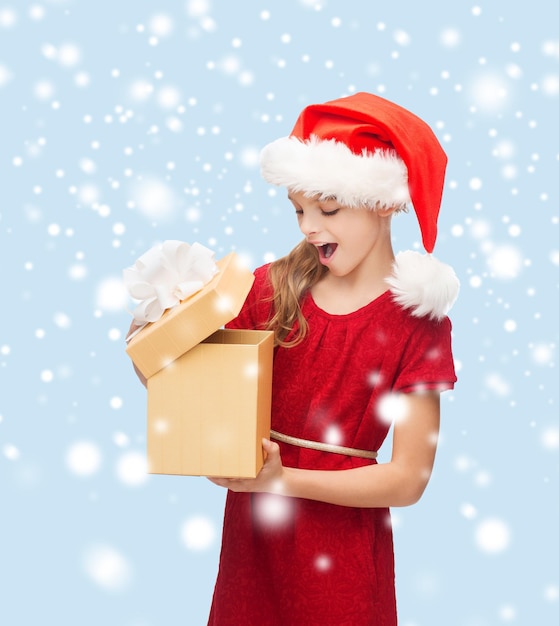 kerst, kerst, winter, geluk concept - lachend meisje in santa helper hoed met geschenkdoos