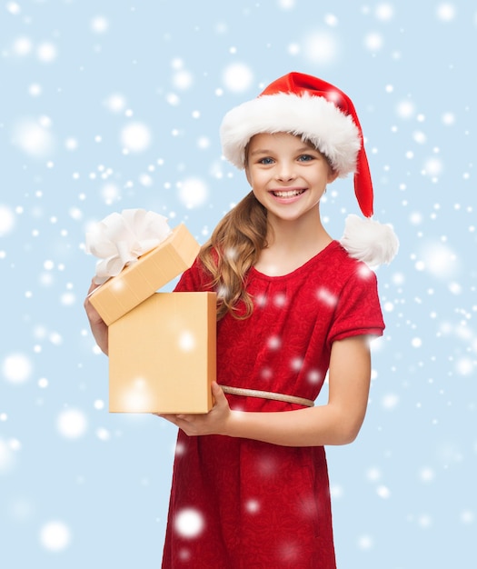 kerst, kerst, winter, geluk concept - lachend meisje in santa helper hoed met geschenkdoos