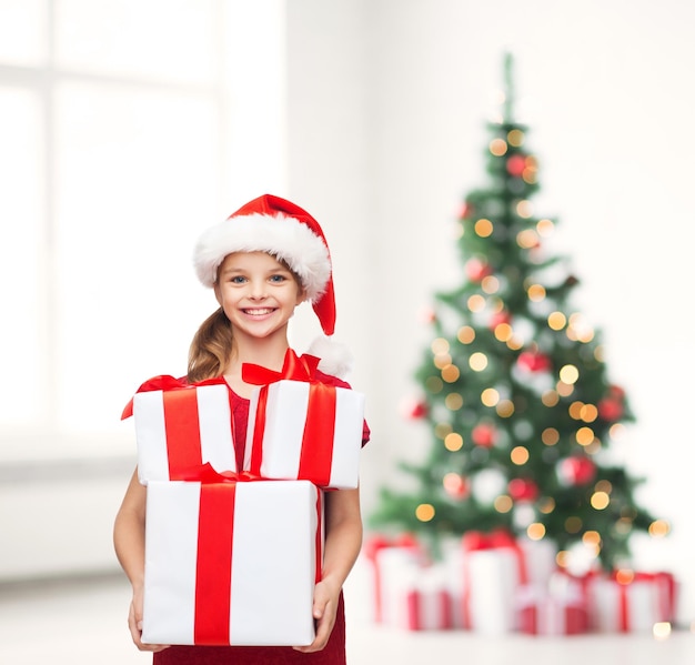 kerst, kerst, winter, geluk concept - lachend meisje in santa helper hoed met veel geschenkdozen