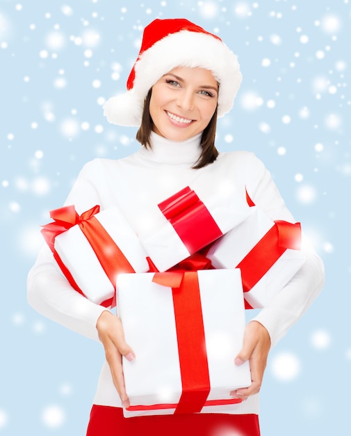 kerst, kerst, winter, geluk concept - lachende vrouw in kerstmuts met veel geschenkdozen