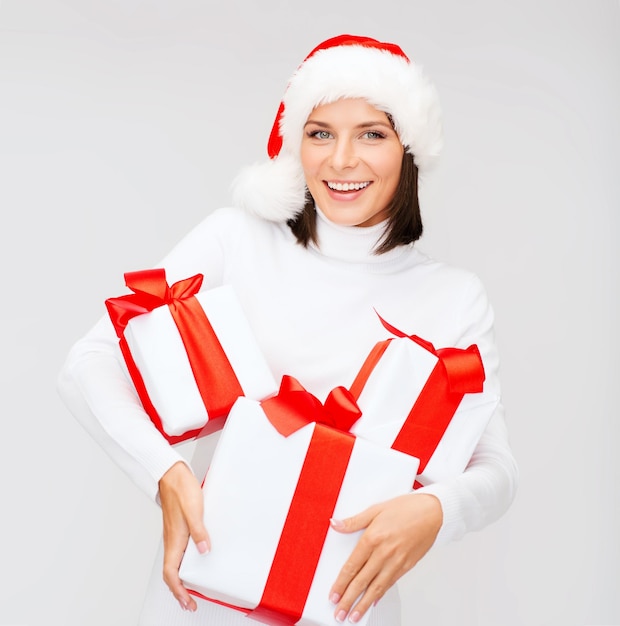 kerst, kerst, winter, geluk concept - lachende vrouw in santa helper hoed met veel geschenkdozen