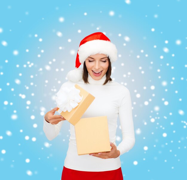 kerst, kerst, winter, geluk concept - verraste vrouw in santa helper hoed met geschenkdoos