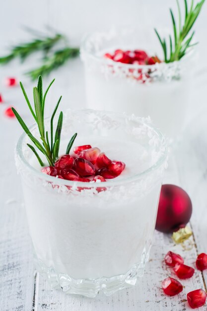 Kerst kokosnoot punch met granaatappelpitjes en takjes rozemarijn op lichte ondergrond