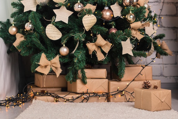 Kerst kunstmatige dennenboom versierd met speelgoed en guirlande geschenken onder de boom