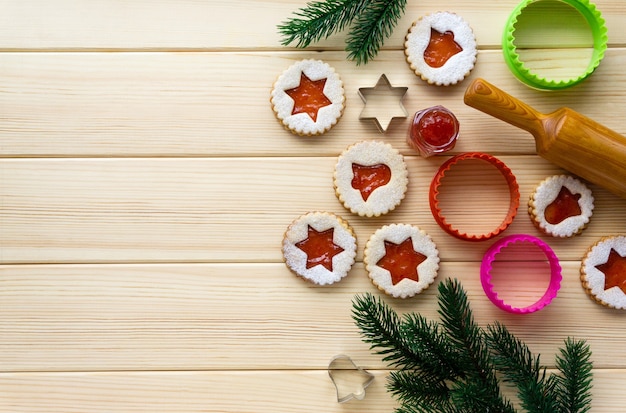 Kerst linzer koekjes met koekjessnijders en deegroller op een houten tafel