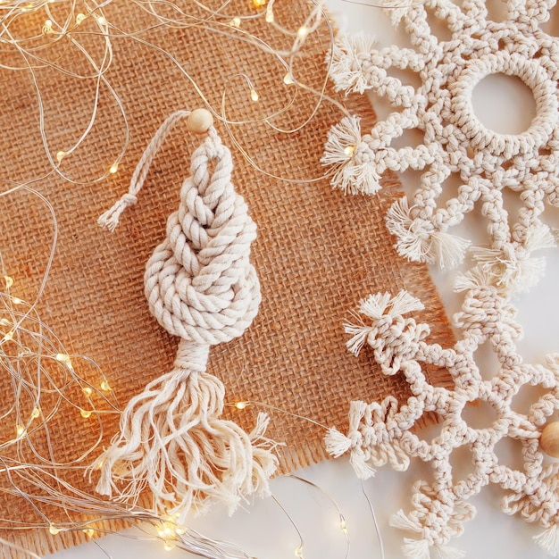 Kerst macrame speelgoed op ambachtelijk papier Witte achtergrond Natuurlijke materialen katoendraad houten kralen en stok Eco-decoratie ornamenten handgemaakt decor Winter- en nieuwjaarsvakantie