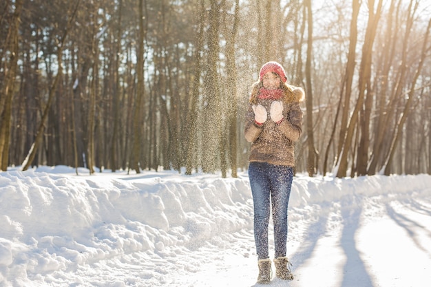 Kerst meisje buiten portret. Winter vrouw waait sneeuw in een park.