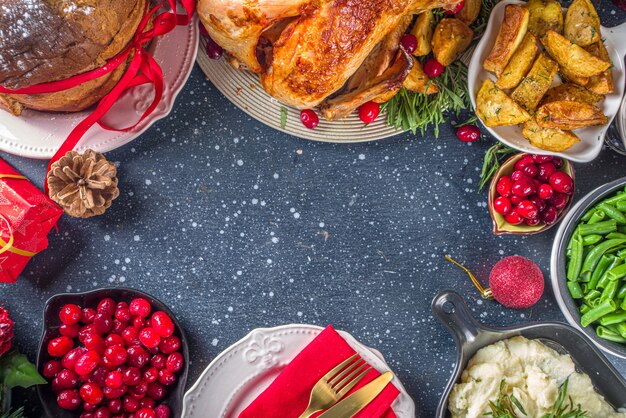 Kerst of Nieuwjaar kalkoen diner. Gebakken kalkoen met aardappel, rode bessen en salieblaadjes, op kersttafel met kerstboom, cadeau en kaarsenachtergrond