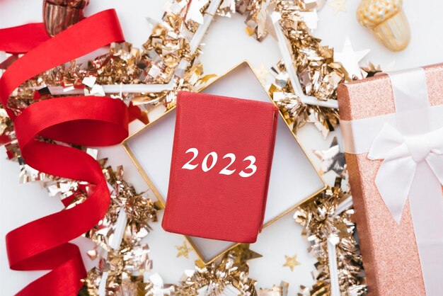 Kerst- of nieuwjaarsachtergrond met figuren van het volgende jaar 2023. Klatergoud, geschenkdoos, rood lint