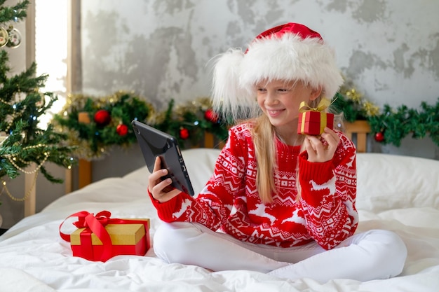 Kerst online gefeliciteerd Lachende vrouw met behulp van mobiele tablet voor video-oproep vrienden en ouders