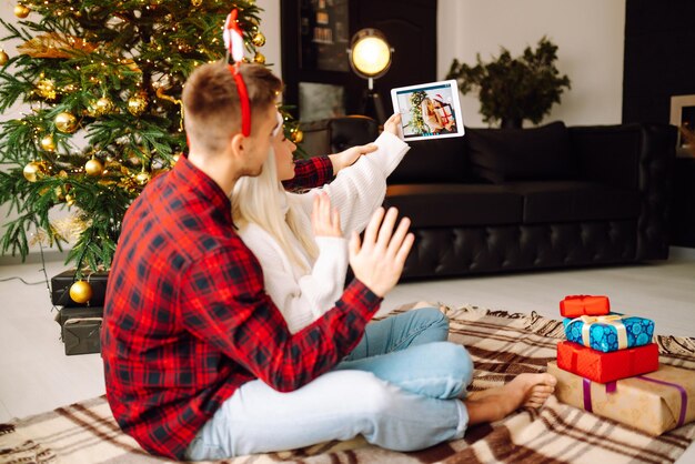 Kerst online vakantie Jong stel met videogesprek met familie of vrienden Virtuele vergadering