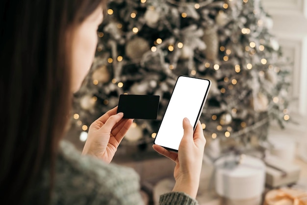 Kerst online winkelen verkoop. Vrouwelijke handen houden de telefoon vast met creditcard