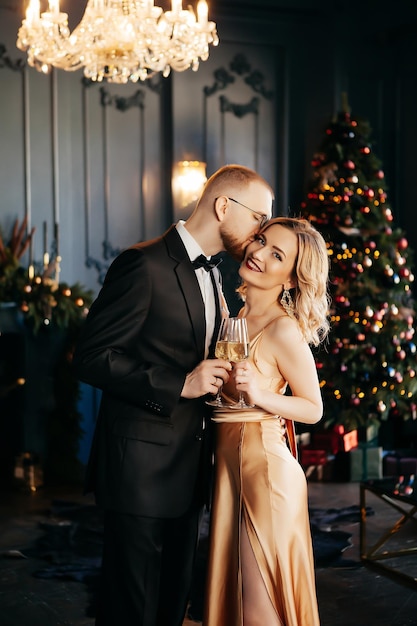 Kerst paar thuis saamhorigheid Man en vrouw drinken champagne knuffelen en lachen in de buurt van de kerstboom