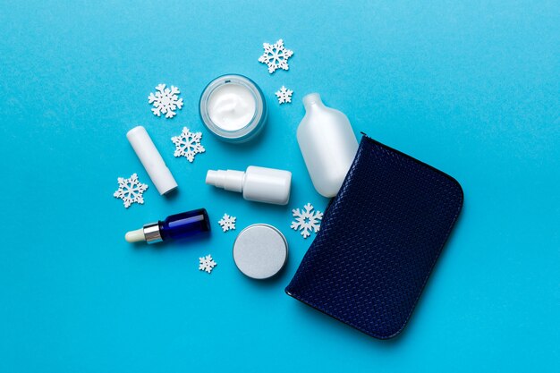 Kerst plat lag met make-up cosmetische producten in cosmetische zak op gekleurde achtergrond. Bovenaanzicht Nieuwjaar Beauty concept.