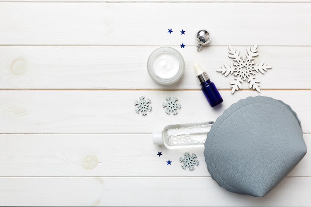 Kerst plat lag met make-up cosmetische producten in cosmetische zak op gekleurde achtergrond. Bovenaanzicht Nieuwjaar Beauty concept