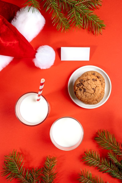 Kerst plat lay-out met melkglazen koekjes lege notitie dennentakken Santas hoed op rood