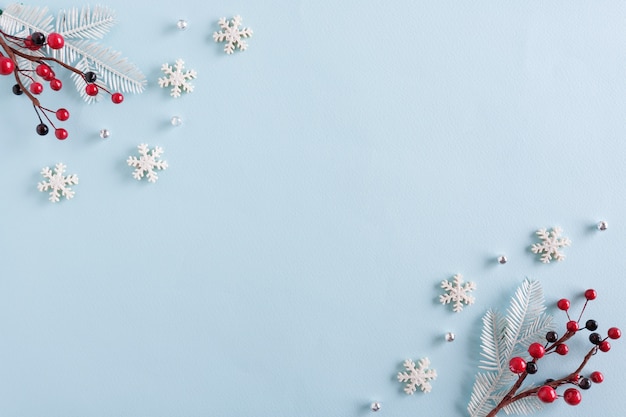 Kerst rand gemaakt van sneeuwvlokken en rode bessen op blauwe ondergrond