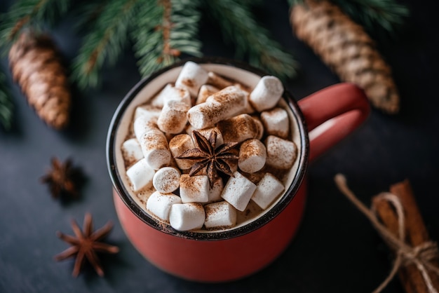 Kerst rode mok warme chocolademelk met marshmallow, kaneel en steranijs met pijnboomtakken en kegels, gezellige kerstachtergrond