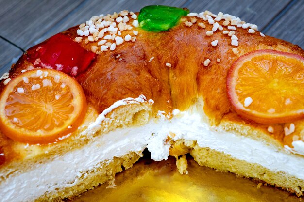 Kerst ronde fruitcake versierd met sparrentak, geglazuurde vruchten en noten op een houten tafel.