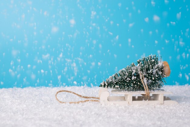 Kerst samenstelling concept. Zijprofiel close-up foto van kleine kleine kerstboom met witte retro sleeën in sneeuw plaats ruimte voor tekst felicitaties wensen