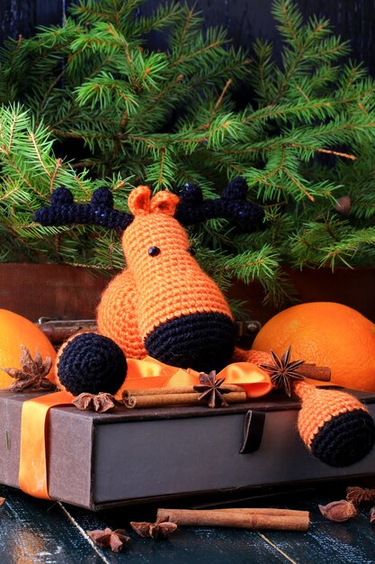 Kerst samenstelling herten cadeau onder de boom met de hand gebreid speelgoed kaneel, anijs mandarijn vuren vintage stijl op oude houten achtergrond