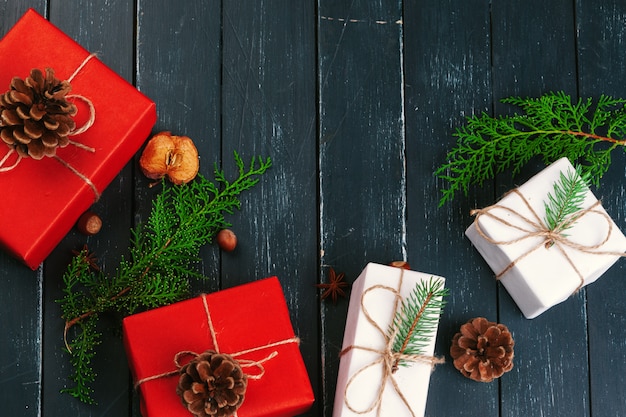 Kerst samenstelling. Kerstcadeau, gebreide deken, dennenappels, dennentakken op houten tafel.