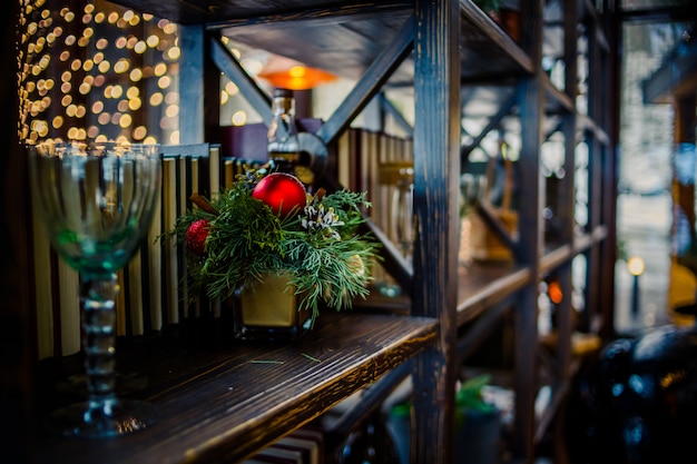 Kerst samenstelling. Kerstmisdecoratie op een boekenplank, houten decor, ornamenten, slinger.