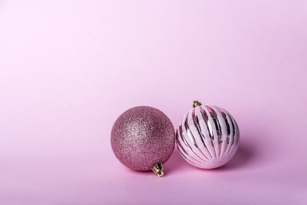 Kerst samenstelling. Twee roze kerstbal, glanzende ballen die op pastelkleurachtergrond hangen
