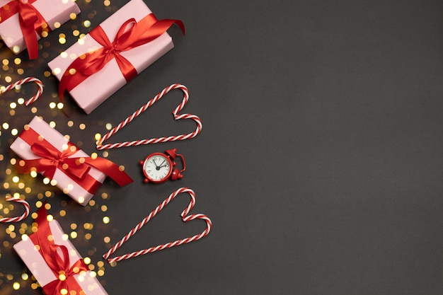 Kerst samenstelling van geschenkdozen met rode linten decor, snoepgoed, klok en goud glitter snoep op donker