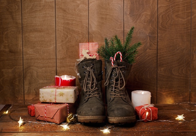 Kerst schoenen op een houten achtergrond rond geschenken, kaarsen branden