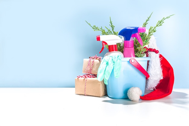 Kerst schoonmaak concept. Diverse flessen, apparatuur en accessoires, handschoenen voor het reinigen met kerstdecor en kerstmuts kopieerruimte. Schoonmaakservice reclame mockup achtergrond