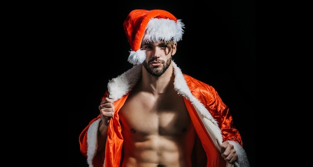 Kerst sexy santa jonge mannen in santa hat strip voor volwassenen Muscle man op xmas Santa met gespierd lichaam knappe sexy santa claus man op zwarte achtergrond