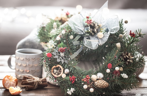 Kerst stilleven van bomen en decoraties, feestelijke krans op een achtergrond van gebreide kleding en mooie cups