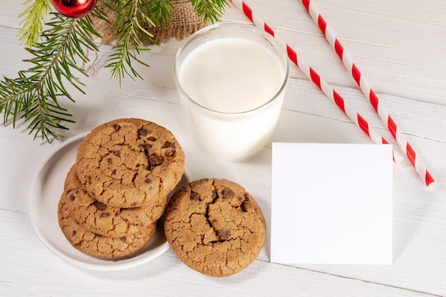 Kerst traditionele melk voor de kerstman met rietjes cookies lege lege notitie op witte houten tafel