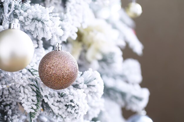 Kerst vakantie achtergrond. Zilveren en gekleurde snuisterij hangend aan een versierde boom met bokeh en sneeuw, kopieer ruimte.