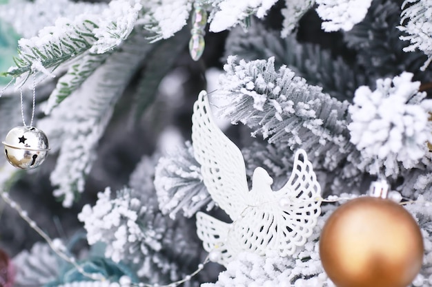 Kerst vakantie achtergrond. Zilveren en gekleurde snuisterij hangend aan een versierde boom met bokeh en sneeuw, kopieer ruimte.