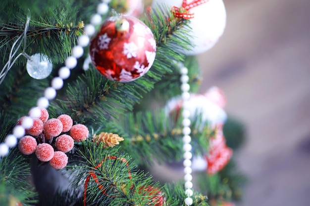 Kerst vakantie achtergrond. Zilveren en gekleurde snuisterij hangend aan een versierde boom met bokeh en sneeuw, kopieer ruimte.