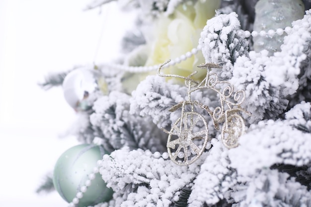 Kerst vakantie achtergrond. Zilveren en gekleurde snuisterij hangend aan een versierde boom met bokeh en sneeuw, kopieer ruimte.