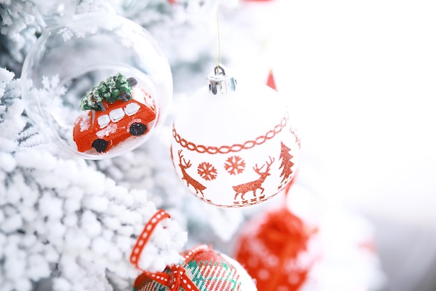 Kerst vakantie achtergrond. Zilveren en gekleurde snuisterij hangend aan een versierde boom met bokeh en sneeuw, kopieer ruimte.
