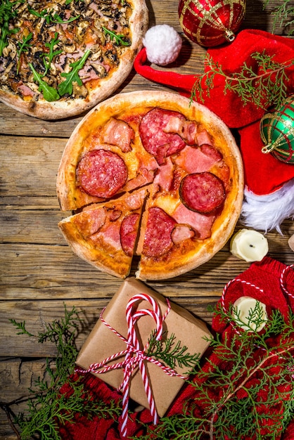 Kerst versierde achtergrond met pizza peperoni en champignons, levering en restaurant Xmas lunch en feestmenu, Santa levert pizza voor Kerstmis, houten klassieke achtergrond bovenaanzicht kopieerruimte