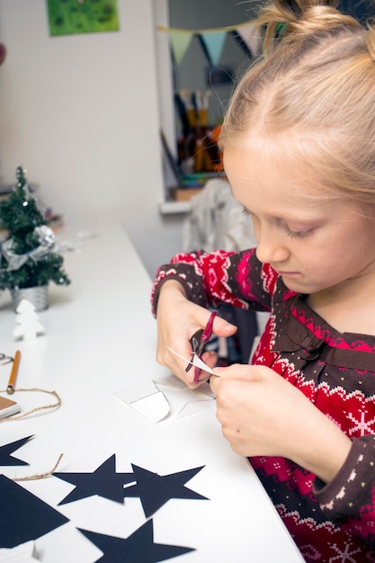 Kerst versiering. klein meisje maakte slingers sterren