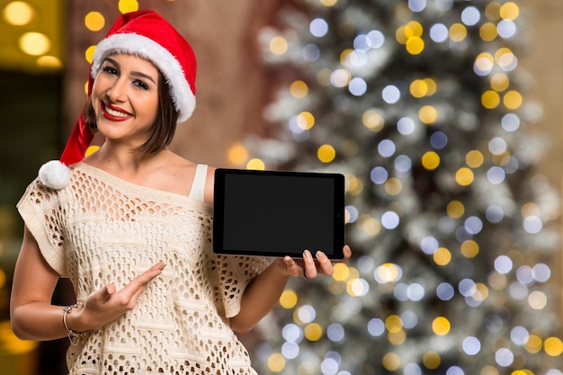 Kerst vrouw portret met tablet. Glimlachende gelukkige vrouw over bokeh Kerstverlichting