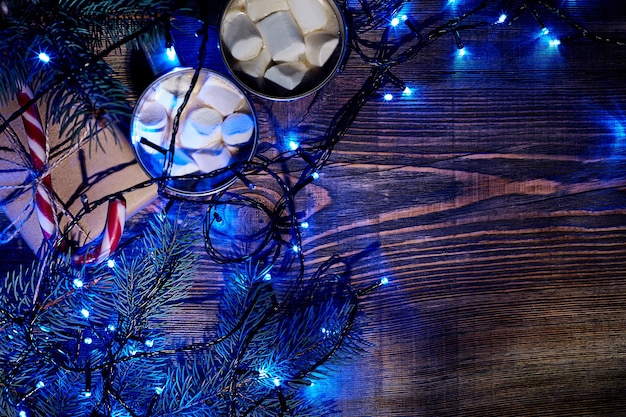 Kerst warme drank. Cacao met marshmallow, geschenkdoos, kerstverlichting, slinger en sparren takken op een houten achtergrond. Bovenaanzicht. Ruimte kopiëren. Plat leggen. Stilleven. Mock-up
