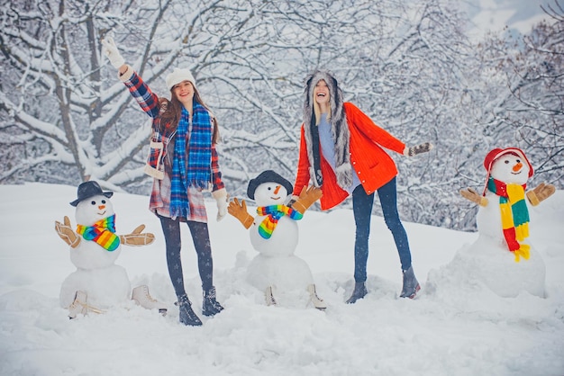 Kerst winter mensen meisjes spelen met sneeuwpop geïsoleerd op sneeuw achtergrond grappige winter mensen ...