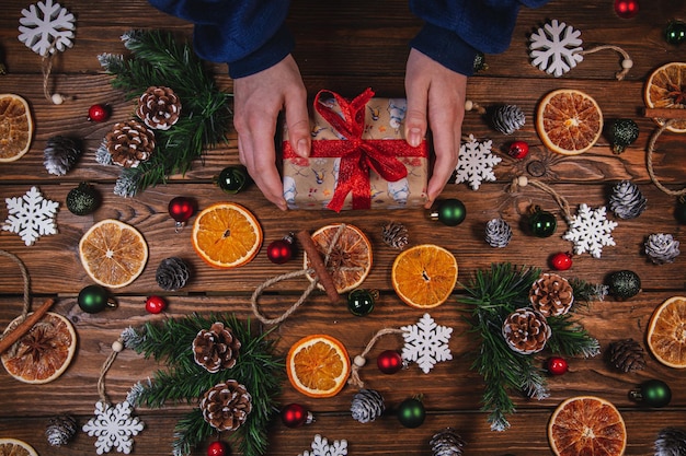 Kerstachtergrond Cadeau in vintage verpakking gedroogde sinaasappelen Kerstspeelgoed en takken Kerstdecor op een houten tafel